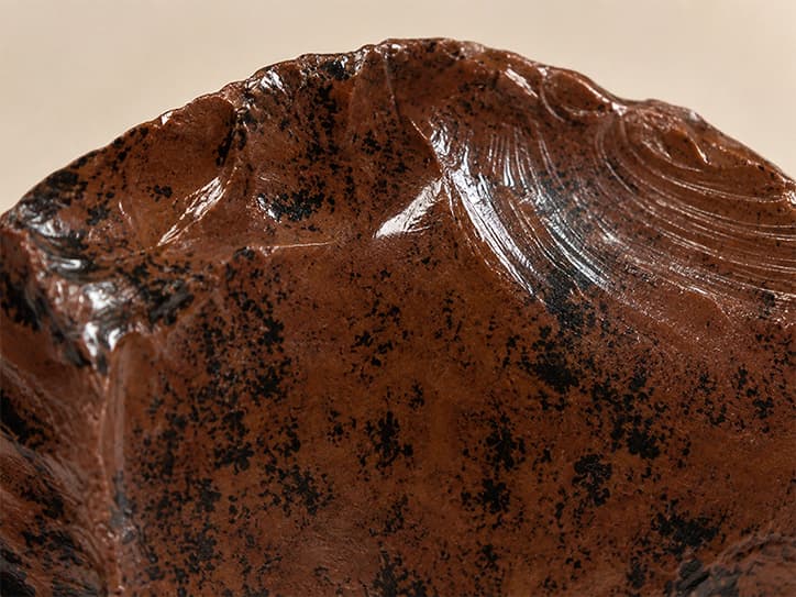 Detailfoto van mahonie-obsidiaan met glasachtige glans en mahoniekleurige tekening