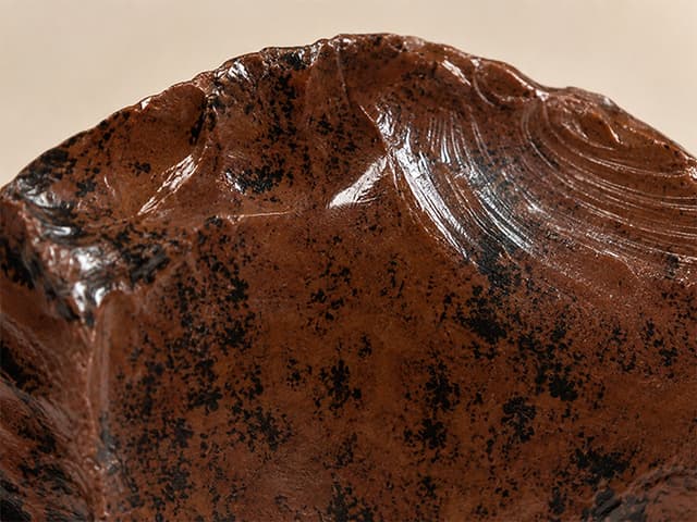 Detailfoto van mahonie-obsidiaan met glasachtige glans en mahoniekleurige tekening